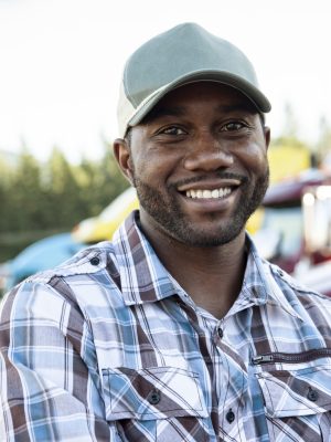 Black man truck driver near his truck parked in a parking lot at a truck stop